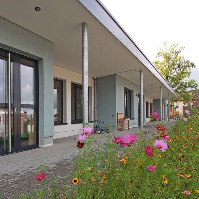 Fassade des Familienzentrums Ratheim mit Blumenwiese