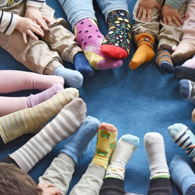 Kinderfüße in bunten Socken im Kreis auf einem blauen Teppich